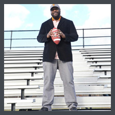 Antron standong on bleachers with a football