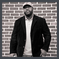 Antron in front of a brick wall with football